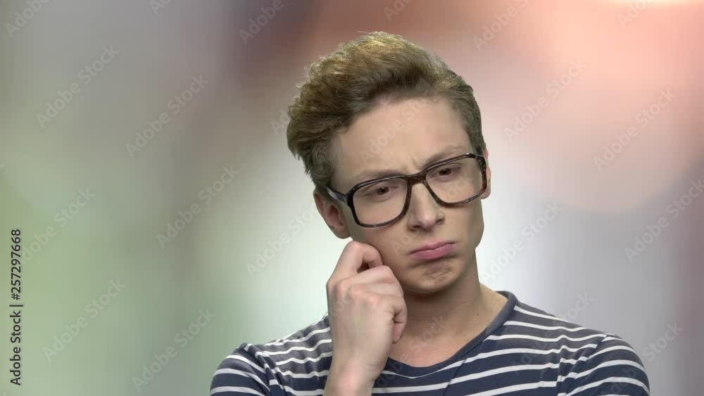 Boy in eyeglasses with thoughtful expression. Teenage nerd boy wearing geek glasses is thinking about new invention. Abstract blurred background. Boy in eyeglasses with thoughtful expression. Teenage nerd boy wearing geek glasses is thinking about new invention. Abstract blurred background.