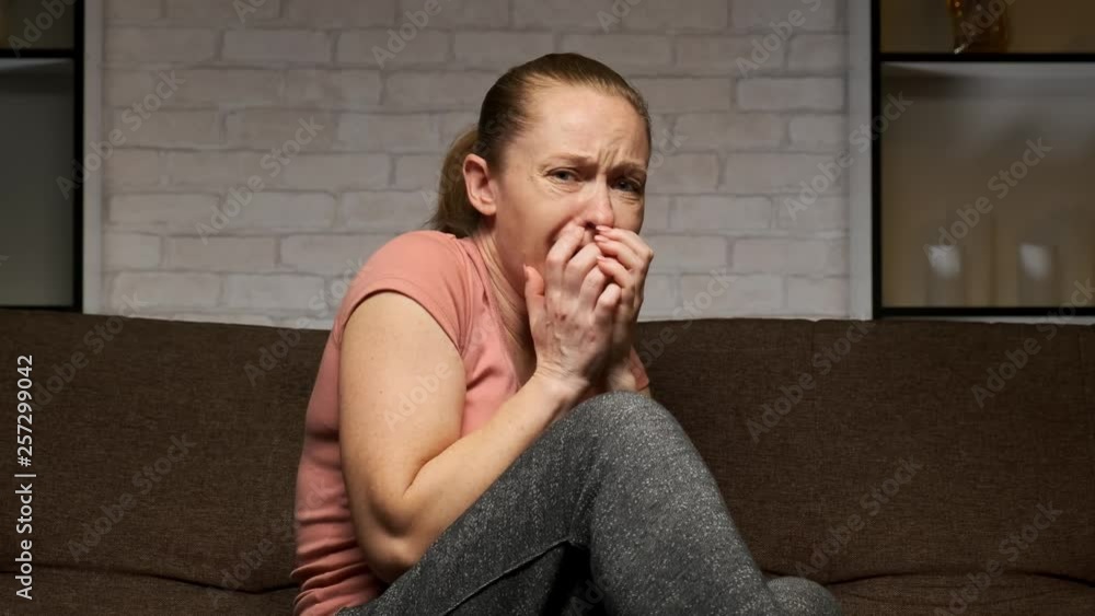 girl feels a sense of fear when watching a scary movie sitting on the couch at home. girl feels a sense of fear when watching a scary movie sitting on the couch at home.