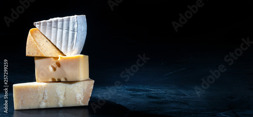 Different kinds of cheese on dark background, copy space