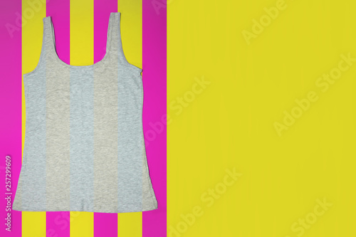 Gray sleeveless female casual tank top on bright striped yellow and pink background. Copyspace. Sport, fitness aparrel. Basic look. photo