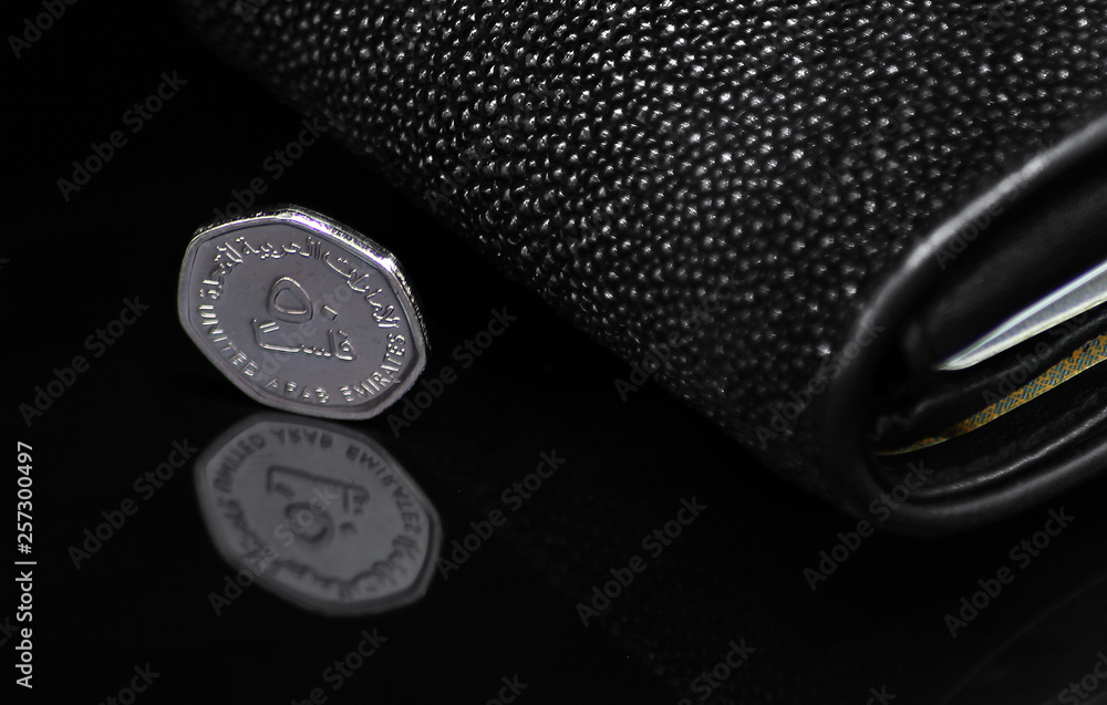 UAE - 50 Fils Coin And Sting Ray Wallet On A Black Shiny Background UAE - 50 Fils Coin And Sting Ray Wallet On A Black Shiny Background