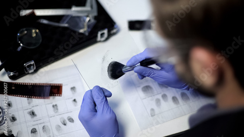 Schilderij op canvas Private detective using powder and brush to take fingerprint from piece of glass