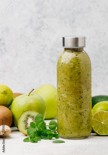 Bottle with green smoothie on grey background with copy space
