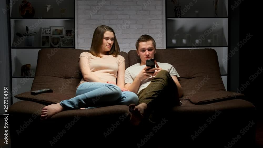 young couple is sitting on the sofa in the living room. young couple is sitting on the sofa in the living room.