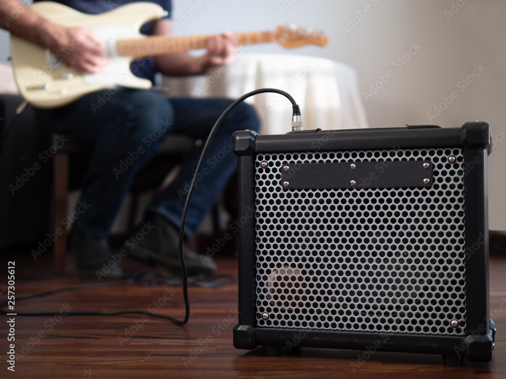 Guitar amplifier close up with man playing guitar in the the background.