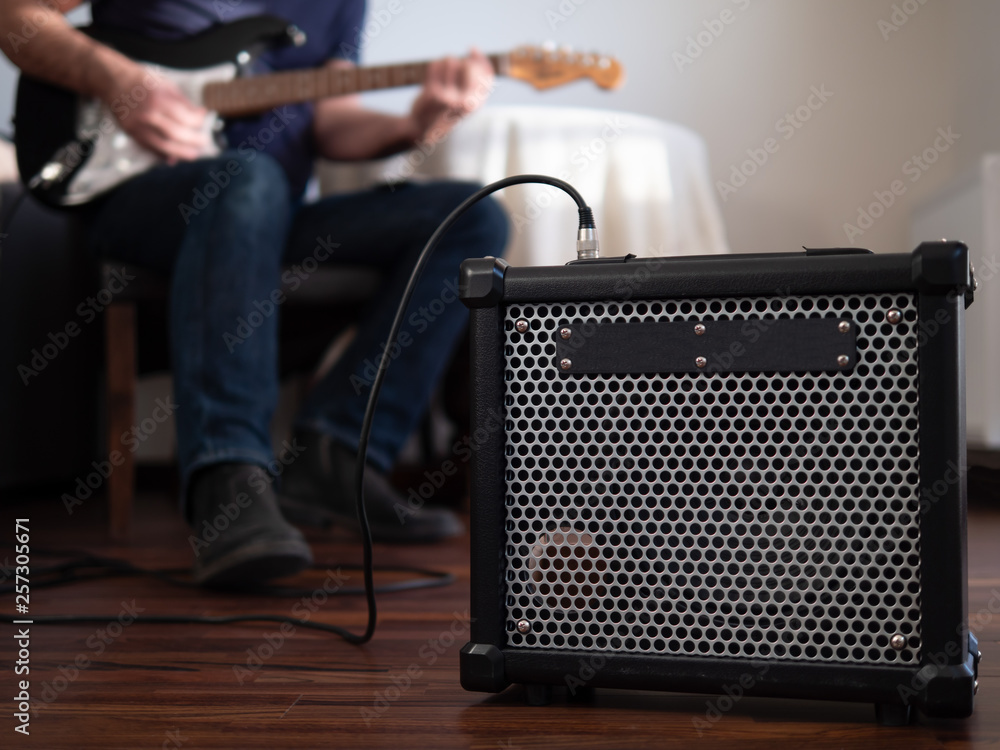 Guitar amplifier close up with man playing guitar in the the background.