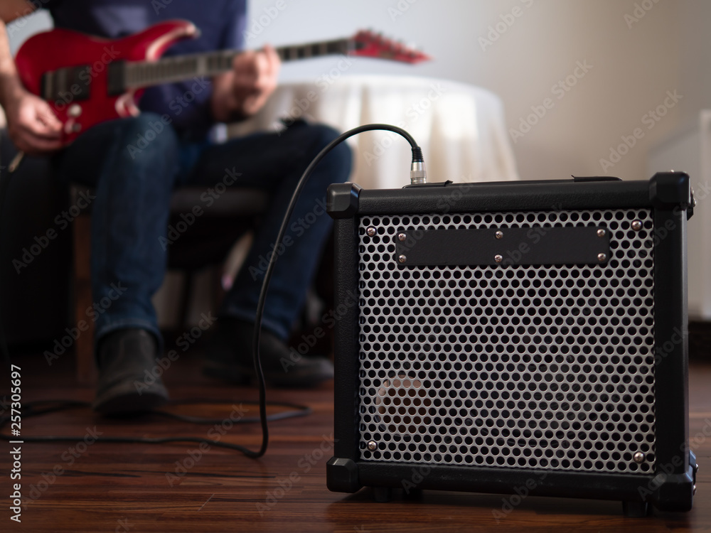 Guitar amplifier close up with man playing guitar in the the background.