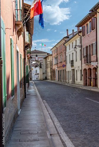 Tableau sur toile Sesto al Reghena, centro storico pedonabile e palazzi entro le mura, con bandier