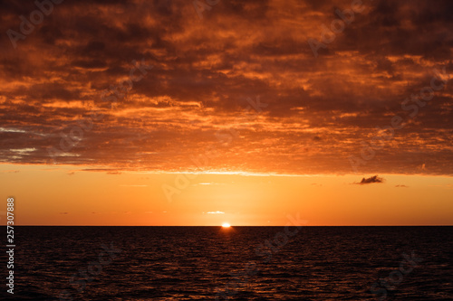 A stunning sunset illuminates clouds drifting above the Caribbean Sea.