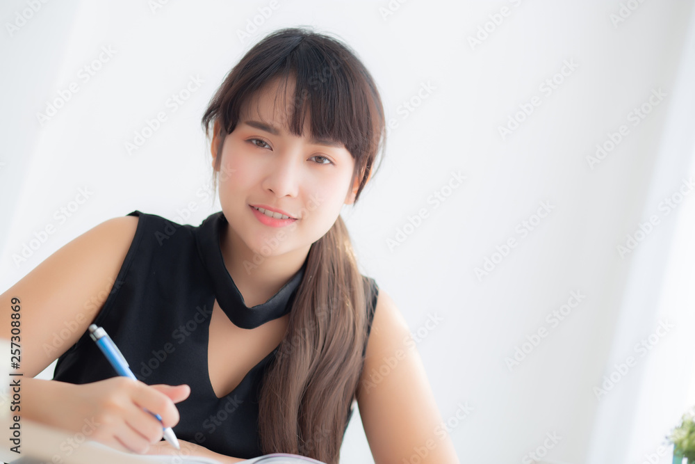 Beautiful young asian woman smiling sitting study and learning writing notebook and diary in the living room at home, girl homework, business woman working on table, education concept. Beautiful young asian woman smiling sitting study and learning writing notebook and diary in the living room at home, girl homework, business woman working on table, education concept.