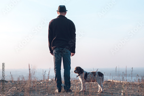 man and his dog standing on barren land