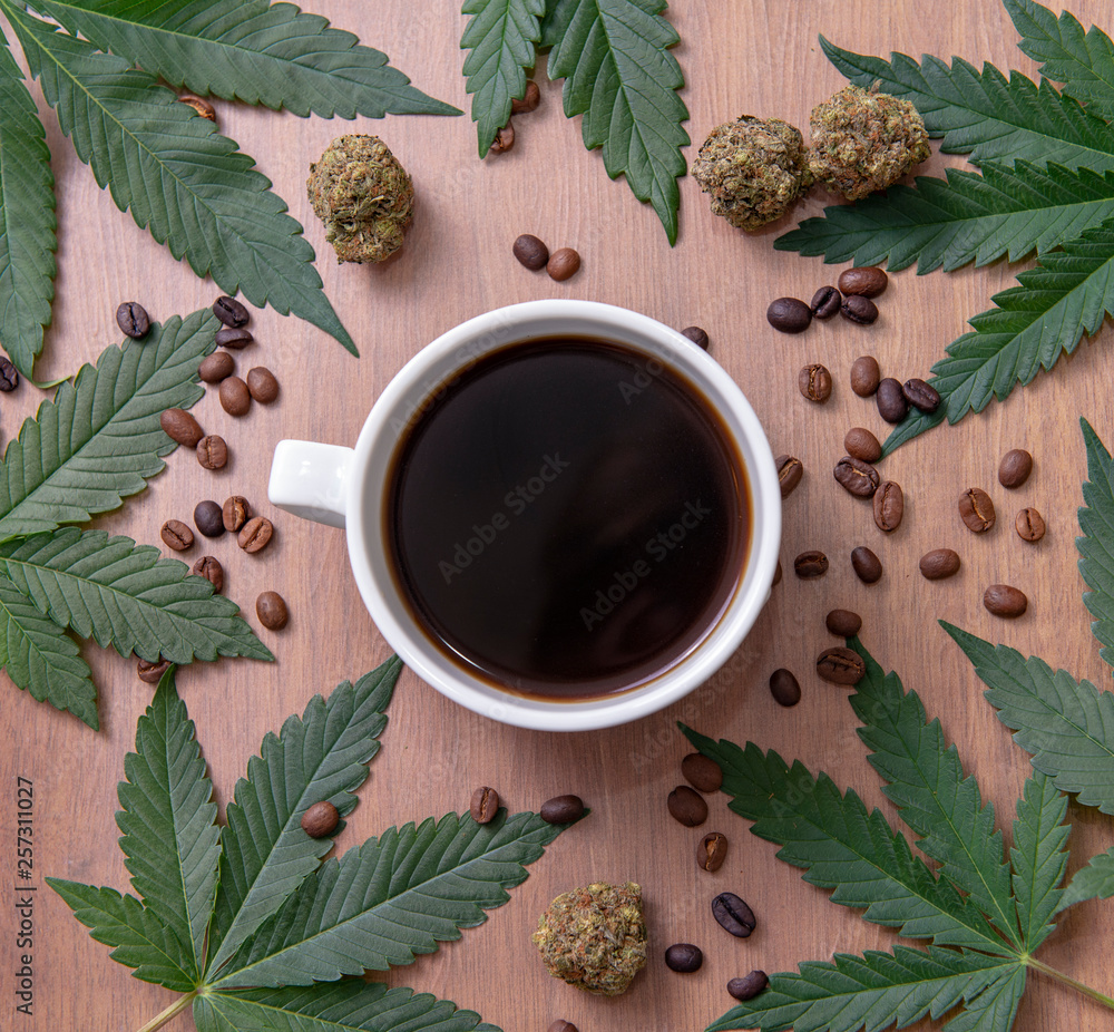 Coffee cup and cannabis with beans, nugs and marijuana leaves over wood