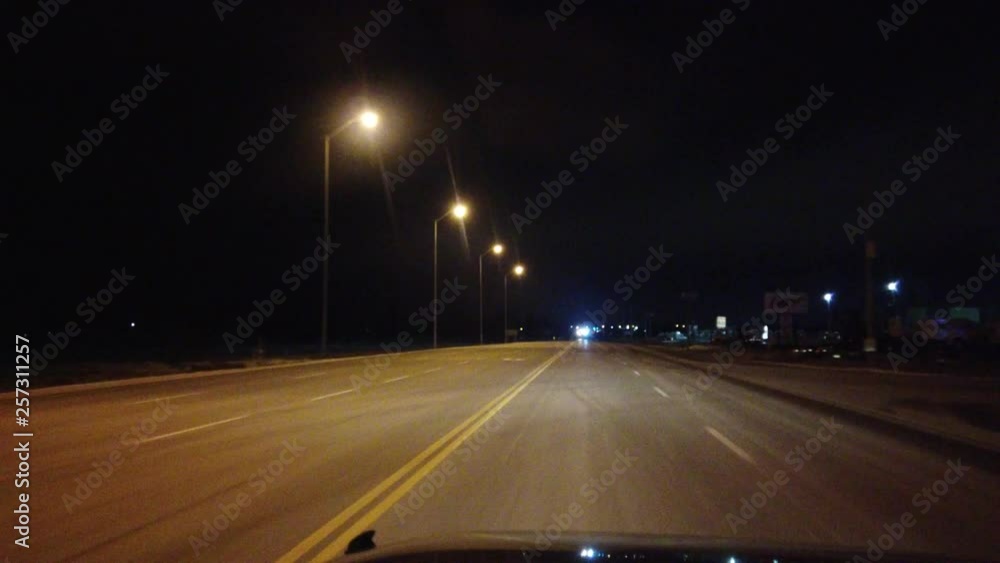 Passing A Car At Night On An Empty Highway With Overhead Street Lamps Passing A Car At Night On An Empty Highway With Overhead Street Lamps