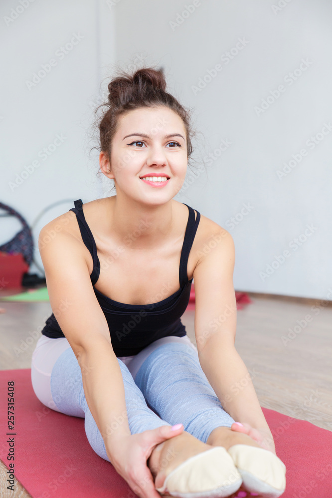 Young and slender girl doing stretching muscles and ligaments on the Mat in the gym. Young and slender girl doing stretching muscles and ligaments on the Mat in the gym.