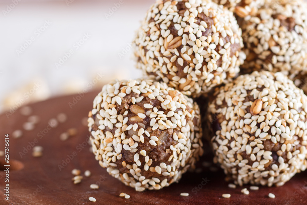 Energy balls cakes with almonds, sesame, cashew, walnuts, dates and germinated wheat, side view, close up.