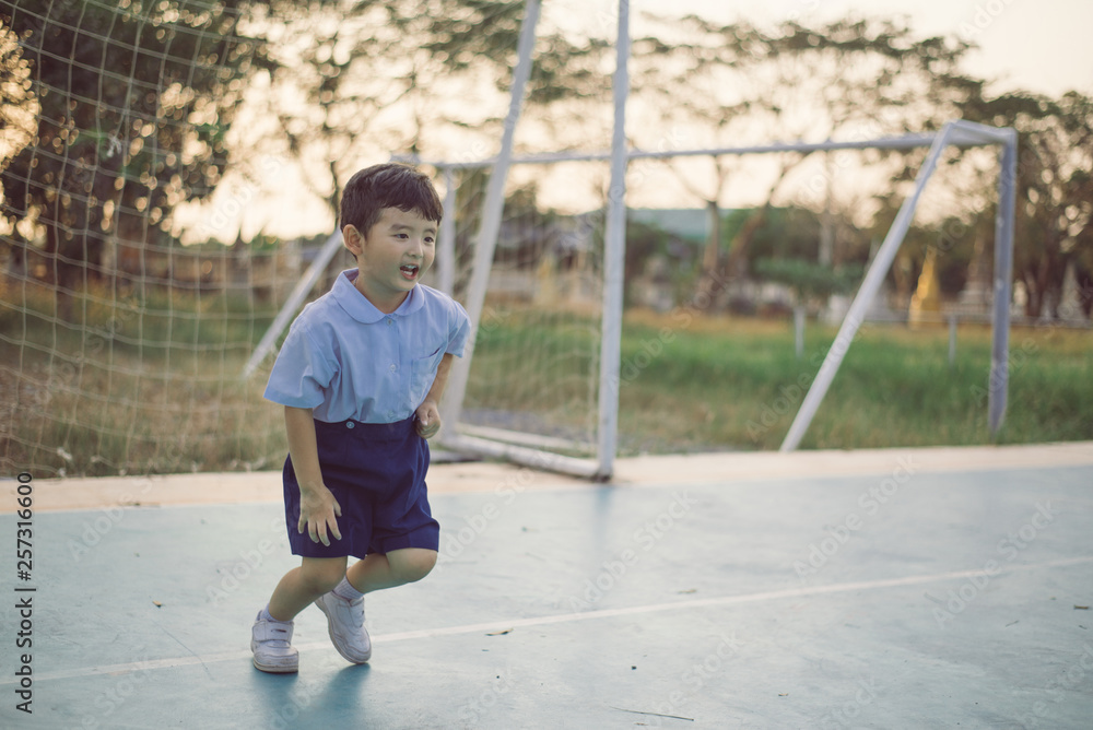 Outdoor portrait of a happy Asian student kid in school uniform smiling.