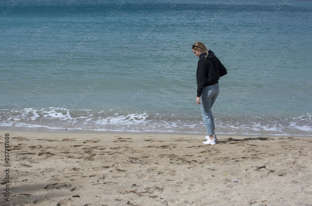 Young cute woman walks on sandy beach in spring
