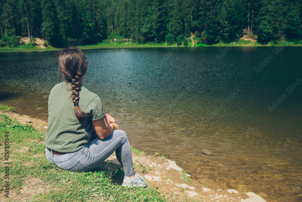 young adult woman sitting at beach of mountains lake in ukraine carpathian mountains young adult woman sitting at beach of mountains lake in ukraine carpathian mountains