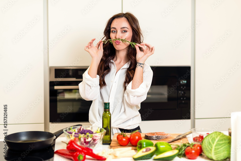 Brunette woman preparing fresh fish steak on the kitchen with vegetables and glass of white wine. Housewife concept Brunette woman preparing fresh fish steak on the kitchen with vegetables and glass of white wine. Housewife concept