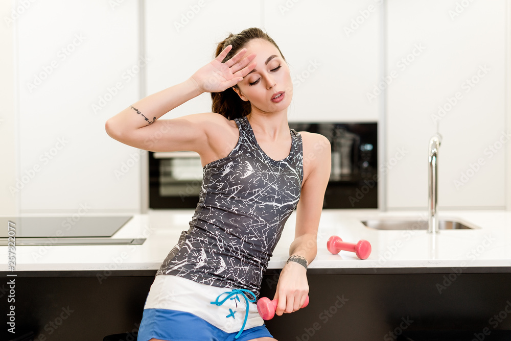 Attractive brunette girl with active fitness lifestyle training at home and taking care of her health and body with dumbbells Attractive brunette girl with active fitness lifestyle training at home and taking care of her health and body with dumbbells