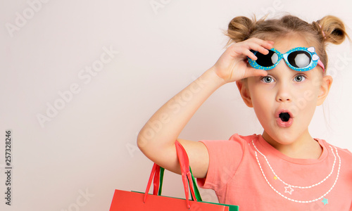 beautiful girl wearing dress and sunglasses holding shopping bags