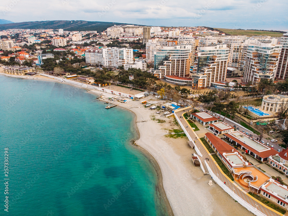 Aerial view of new modern buildings at sea coastline near sand beach, Gelendzhik city - resort on black sea for summer tourism and vacation, view from water, drone shot