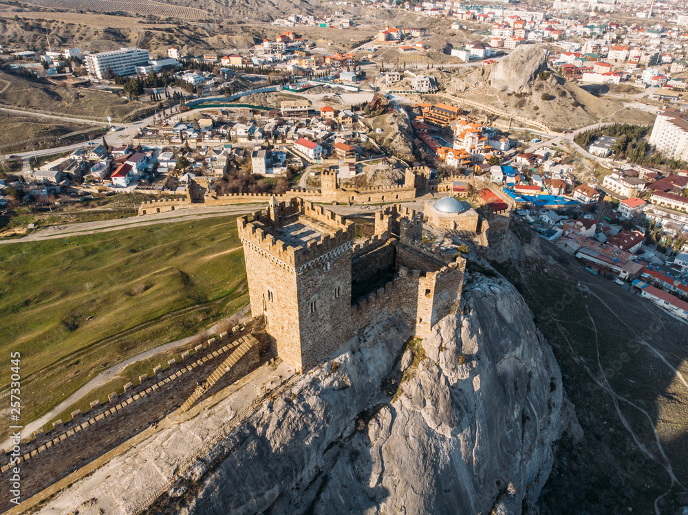 Genoese fortress in Sudak, Crimea. Aerial panorama view of ruins of ancient historic castle or fortress on crest of mountain near sea. Beautiful summer tourist landscape