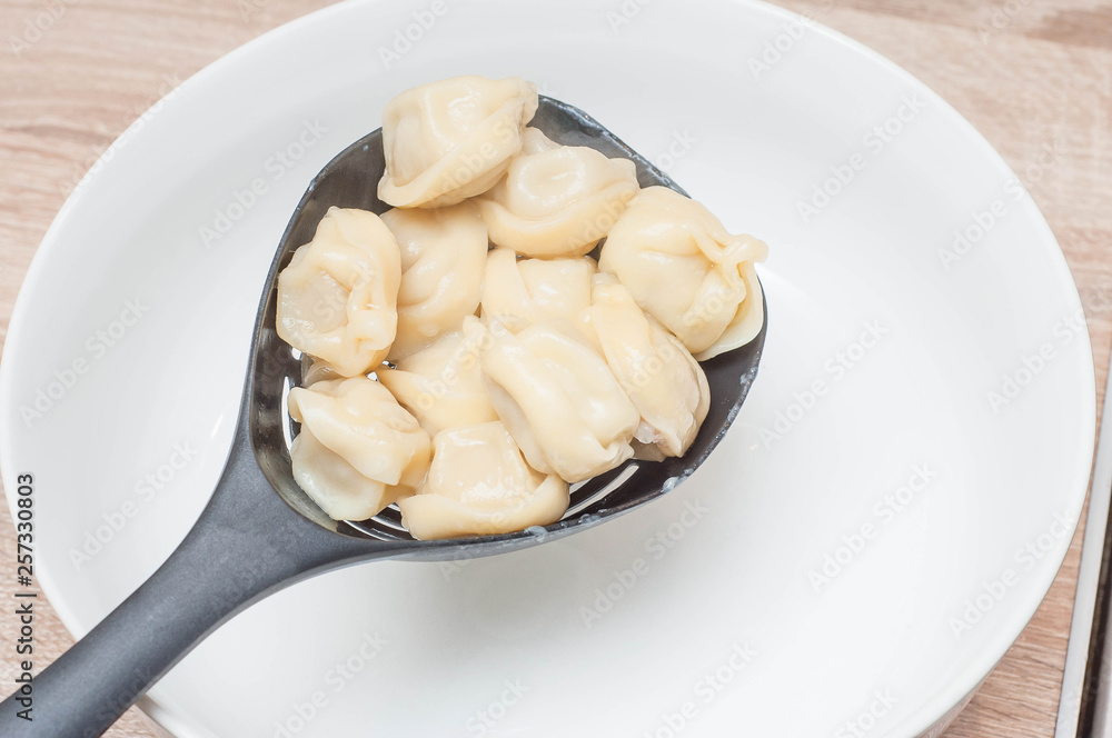 Sieve with dumplings on the background of a white plate ready to serve Sieve with dumplings on the background of a white plate ready to serve