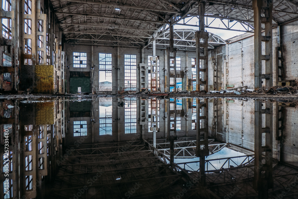 Inside of flooded dirty abandoned ruined industrial building with water reflection 