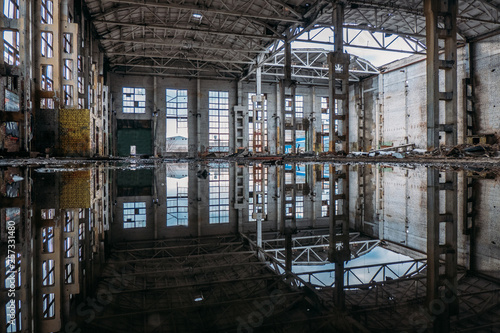 Inside of flooded dirty abandoned ruined industrial building with water reflection 
