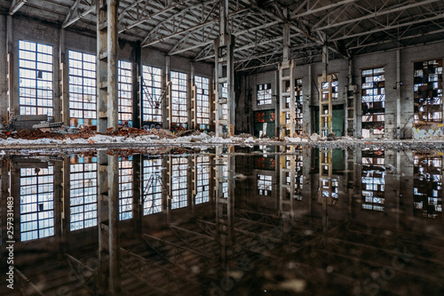 Inside of flooded dirty abandoned ruined industrial building with water reflection 