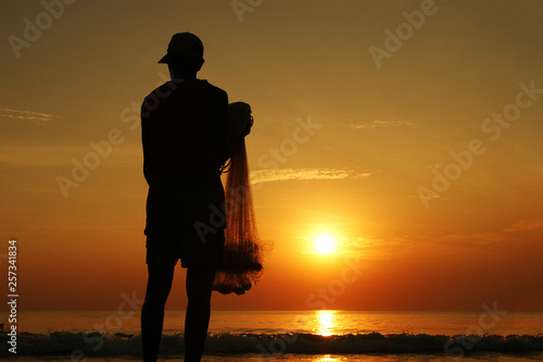 morning fishing. silhouette of a fisherman with a net at sunrise