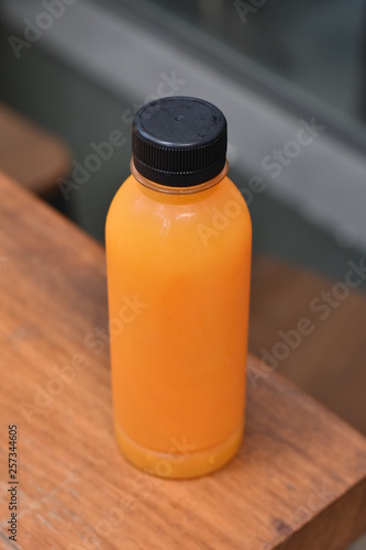 A plastic bottle of fresh orange juice on wooden table