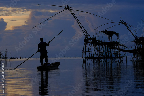Silhouette of Local fisherman started his work early morning, in the golden sunrise in the wetland Talay Noi, Pattalung Province, Thailand.