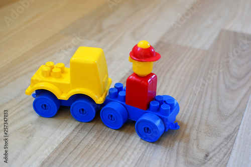 Toy car made of colorful plastic blocks on wooden texture floor background. Concept of educational and developing toys for children.