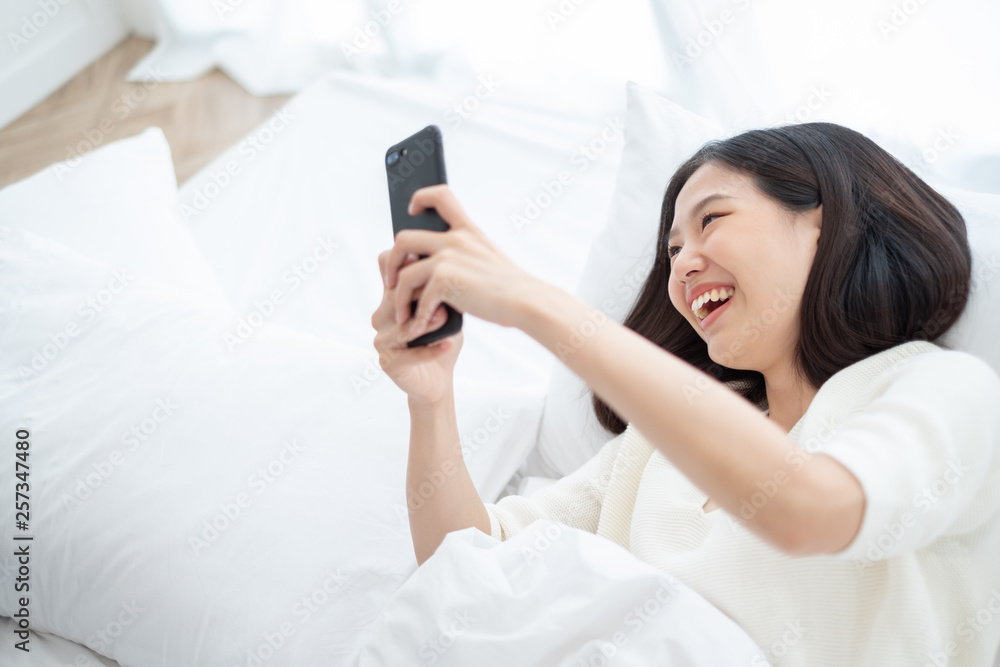 Beautiful Asian woman using smart phone in bed room for online shopping, Asian woman lifestyle concept Beautiful Asian woman using smart phone in bed room for online shopping, Asian woman lifestyle concept