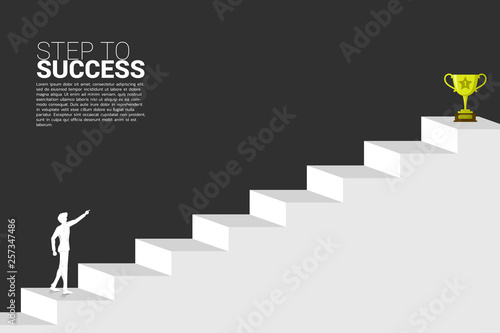 silhouette of businessman point to trophy at top of stair. Concept of vision mission and goal of business