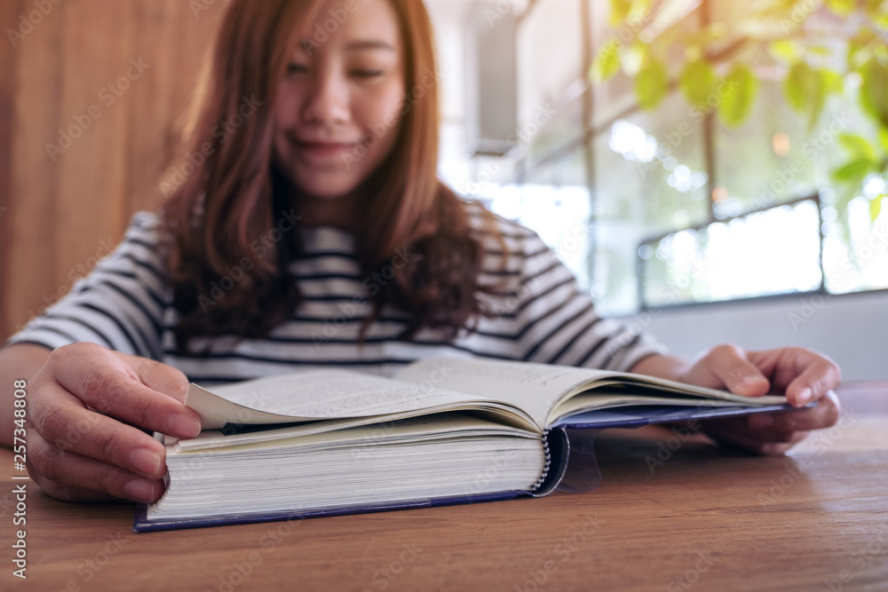 Closeup image of a beautiful asian woman holding and reading a book Closeup image of a beautiful asian woman holding and reading a book