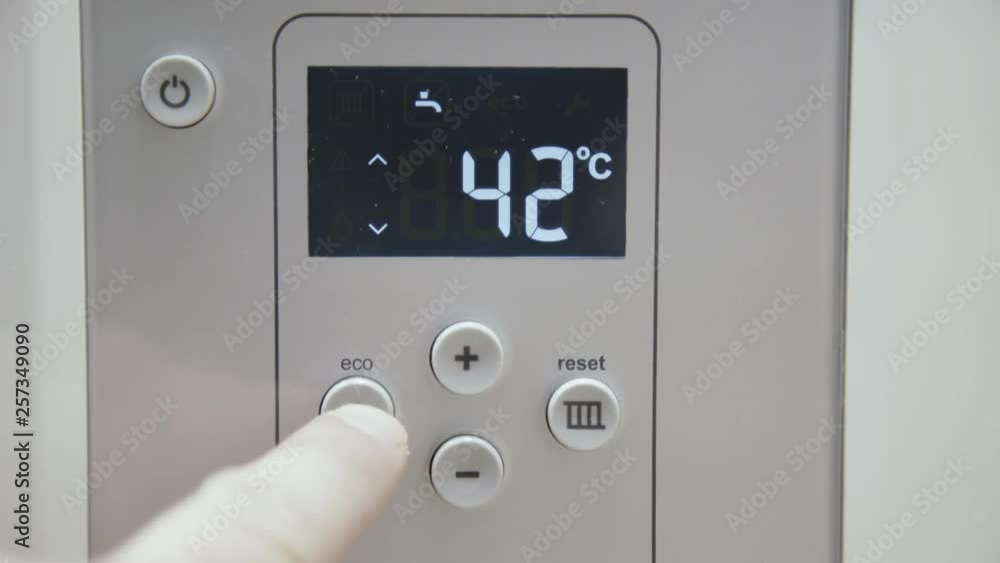 Male finger touches boiler display for temperature control Male finger touches boiler display for temperature control