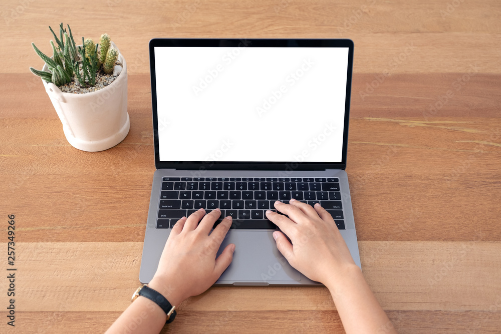 Top view mockup image of a woman using and typing on laptop with blank white screen on wooden table Top view mockup image of a woman using and typing on laptop with blank white screen on wooden table