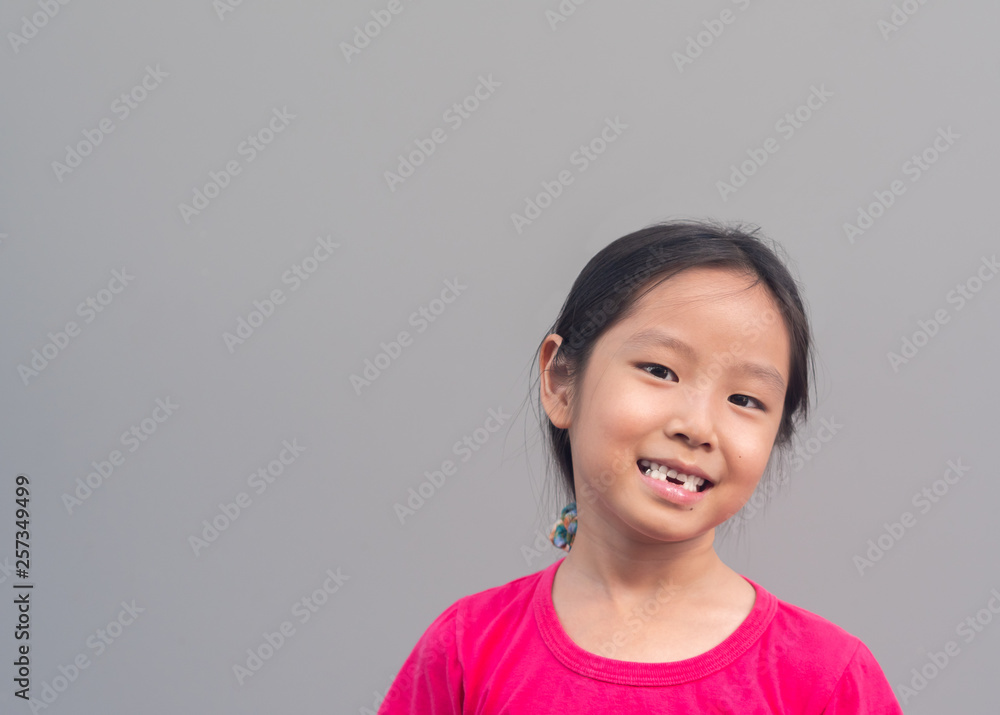 Asian little cute girl smile with her broken tooth , grey background Asian little cute girl smile with her broken tooth , grey background