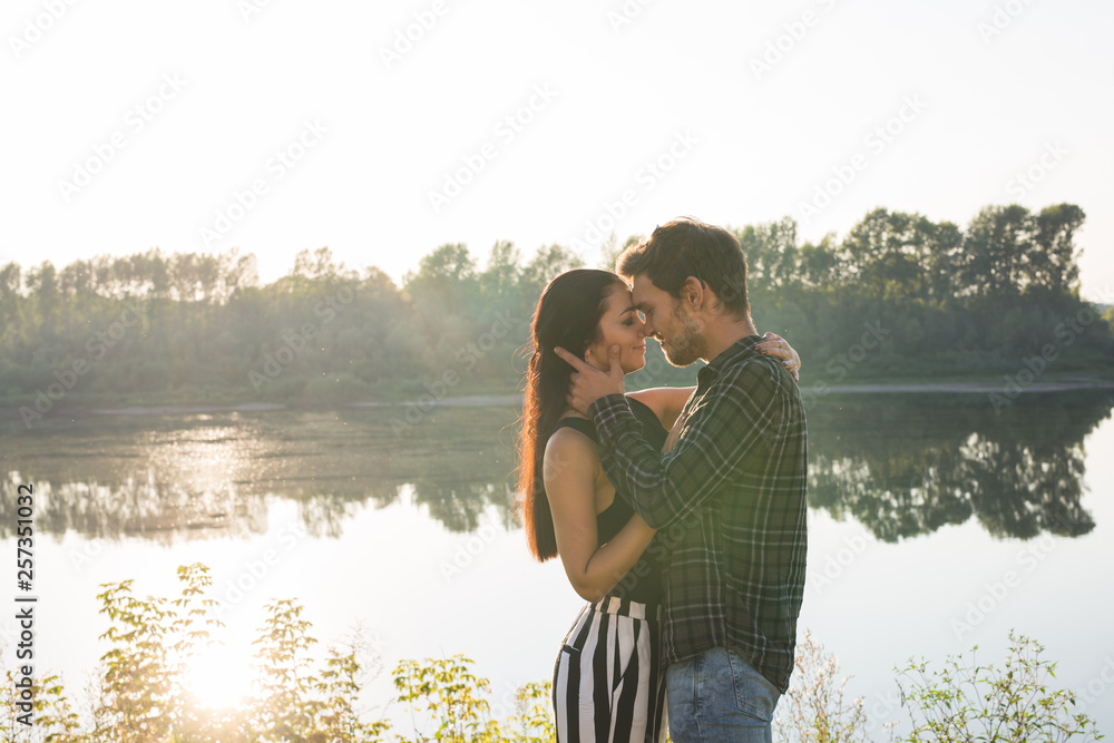 Relationship, love and nature concept - Close up portrait of attractive woman and handsome man hugging on the background of the lake