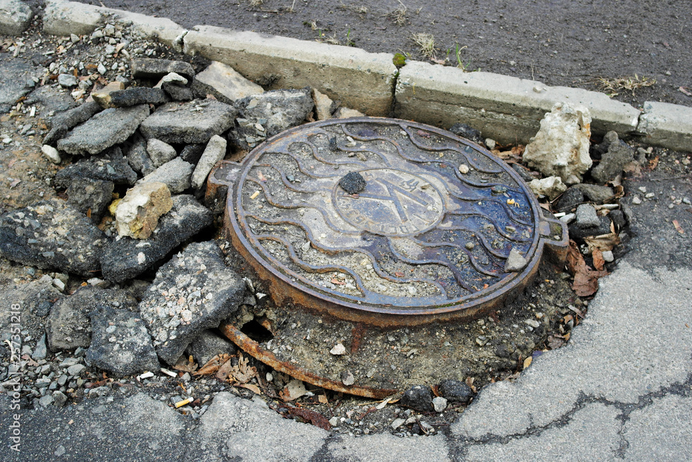 manhole against broken asphalt
