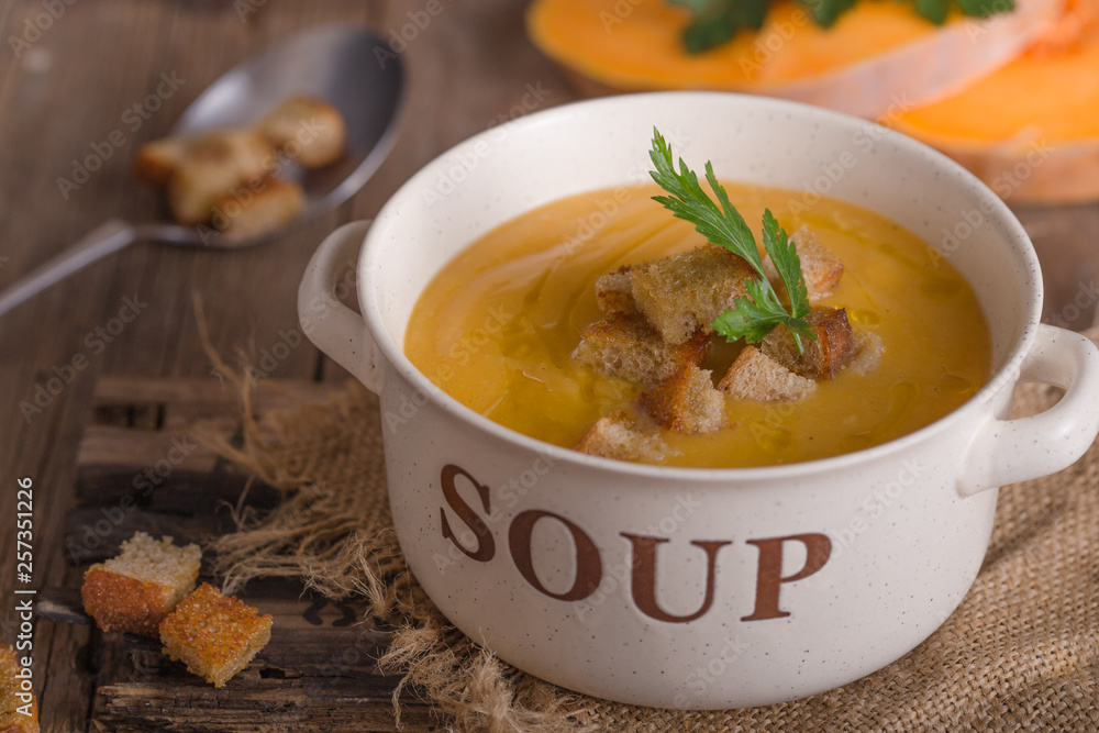 Pumpkin soup and organic pumpkins on wooden table. Seasonal autumn food - Spicy pumpkin soup in bowl. Pumpkin soup and organic pumpkins on wooden table. Seasonal autumn food - Spicy pumpkin soup in bowl.