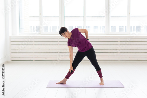 Fototapeta Naklejka Na Ścianę i Meble -  Yoga, people concept - a middle-aged woman doing a yoga and try to do a asana