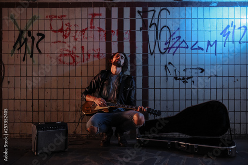 Fotografija A street musician playing on guitar in the underpass