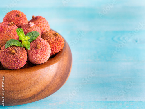 lychee fruit in clay plate on blue wooden background close up photo