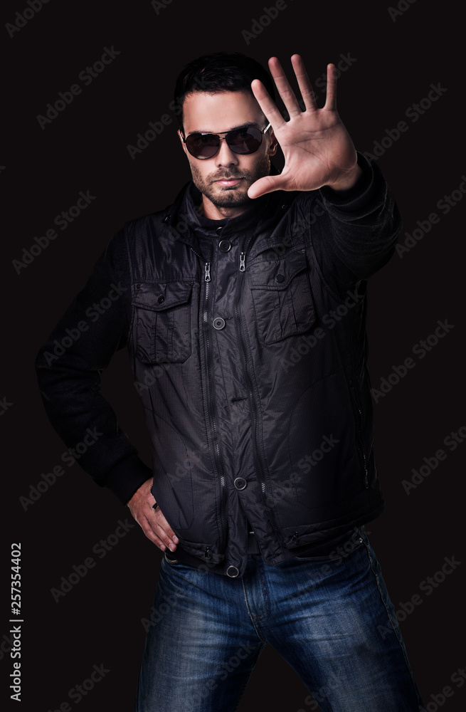 Fototapeta premium Handsome young man in sunglasses shows stop gesture.