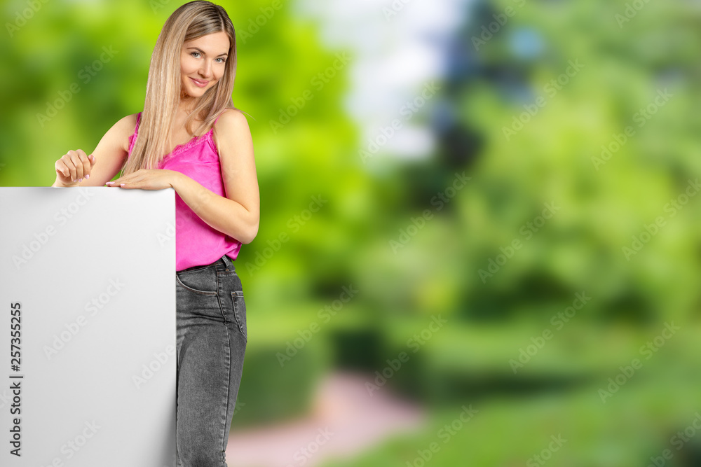 Happy smiling beautiful young woman in pink smart casual clothing showing blank signboard or copyspace for slogan or text Happy smiling beautiful young woman in pink smart casual clothing showing blank signboard or copyspace for slogan or text
