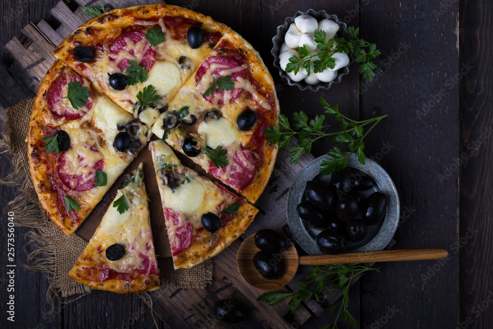 Pizza served with dill. Pizza with tomatoes black olives and ham.
